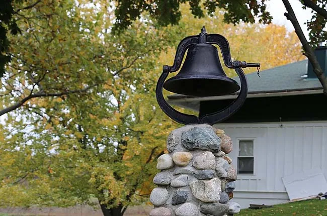 An old iron bell on a fieldstone post