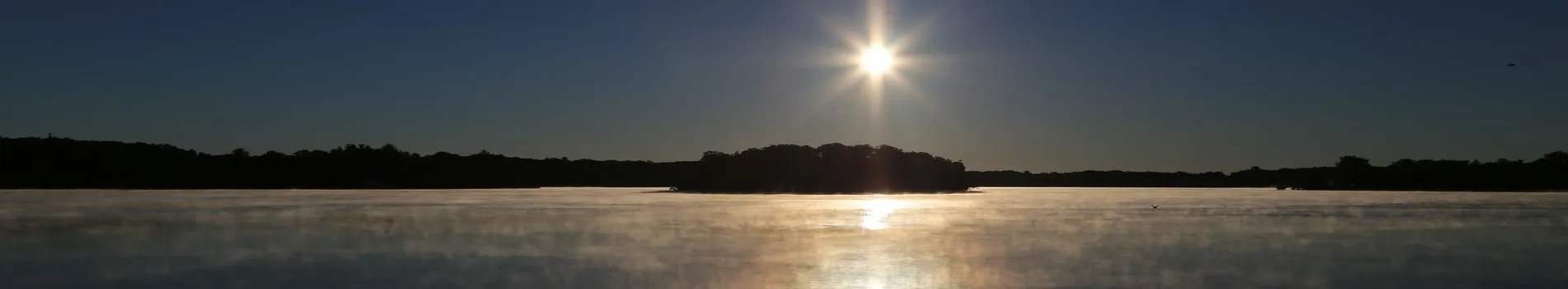 The sun over the island on Lake Angelus